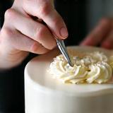 Hands decorating a cake.